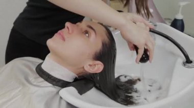 Güzel genç kız kuaförde saçlarını yıkıyor..