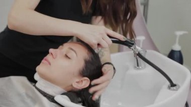 Güzel genç kız kuaförde saçlarını yıkıyor..