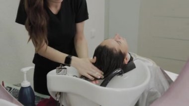 Güzel genç kız kuaförde saçlarını yıkıyor..