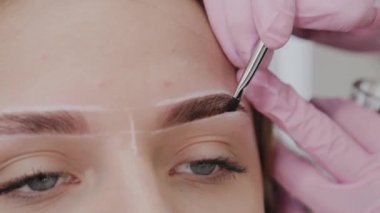 Profesyonel makyöz müşteriye kına ile kaş çizer.
