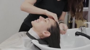 Kız kuaför müşterinin kafasına şampuan koyar..