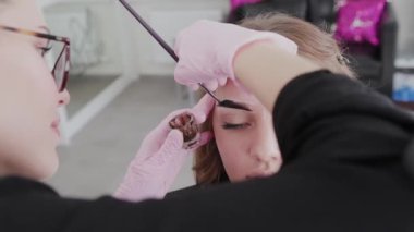 Profesyonel makyöz müşteriye kına ile kaş çizer.
