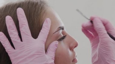 Profesyonel makyöz müşteriye kına ile kaş çizer.