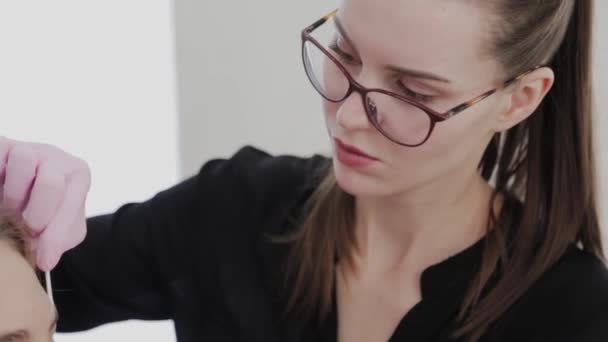 Make-up umělec mazá obočí klienta gelem před zákrokem. — Stock video