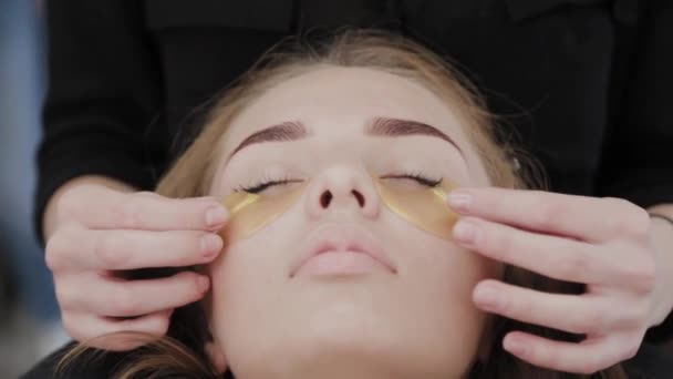 Makeup καλλιτέχνης αφαιρεί μια χρυσή μάσκα από τα μάτια του πελάτη. — Αρχείο Βίντεο