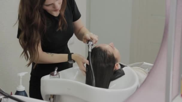 Gadis muda yang cantik mencuci rambut mereka di penata rambut . — Stok Video