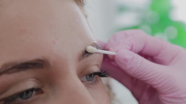 Makeup καλλιτέχνης λιπαίνει τα φρύδια του πελάτη με τζελ πριν από τη διαδικασία. — Αρχείο Βίντεο