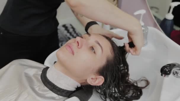 Hermosa joven lavarse el pelo en la peluquería . — Vídeo de stock