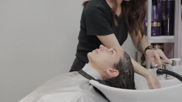 Piękna młoda dziewczyna umyć włosy u fryzjera. — Wideo stockowe