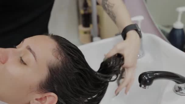 Vacker ung flicka tvätta håret på frisören. — Stockvideo