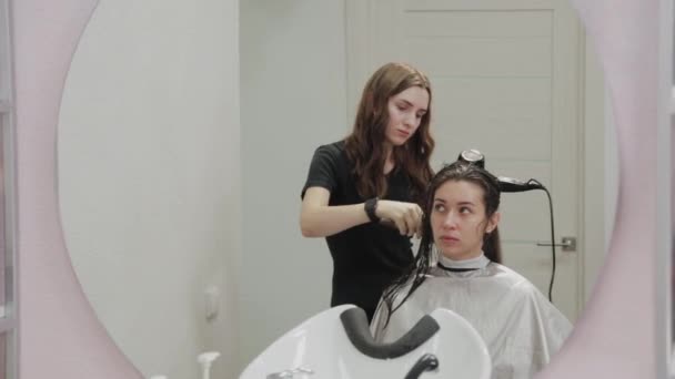 Girl hairdresser dries hair to client with hairdryer at hairdresser. — Stock Video