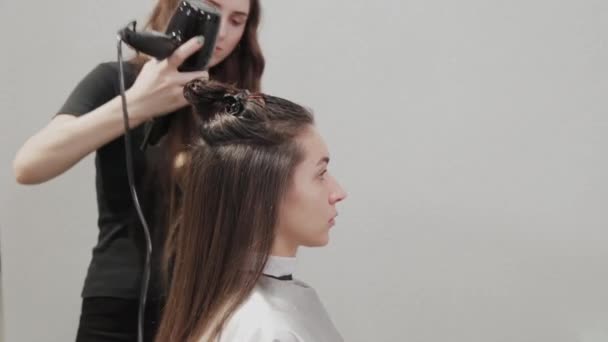 Dívka kadeřník suší vlasy na klienta s fénem na kadeřnictví. — Stock video