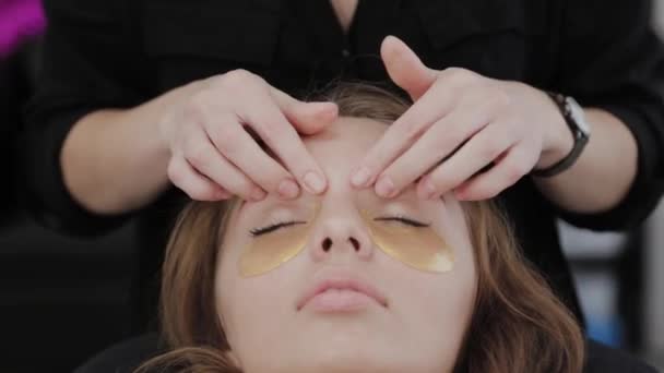 Chica joven en un salón de belleza haciendo masaje facial . — Vídeo de stock