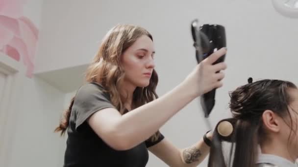 女理发师在理发店用吹风机把头发烘干给顾客. — 图库视频影像