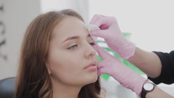 Makeup artist smörjer ögonbrynen på klienten med gel innan förfarandet. — Stockvideo