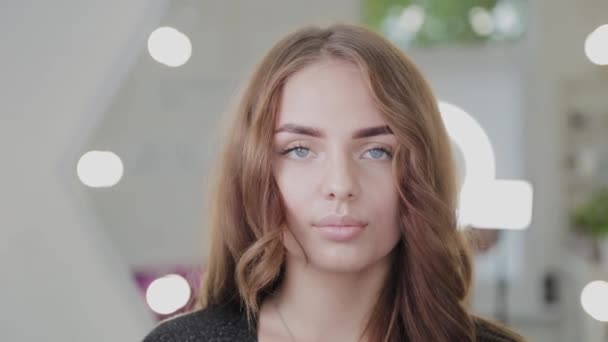 Belle fille dans un salon de beauté près du miroir rétroéclairé. Portrait de femme . — Video