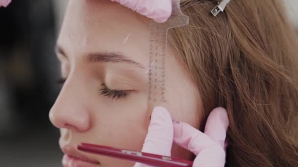 Professionele make-up kunstenaar doet wenkbrauw markup voor klant meisje. — Stockvideo