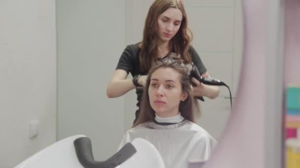 Fille coiffeuse sèche les cheveux au client avec sèche-cheveux chez le coiffeur . — Video