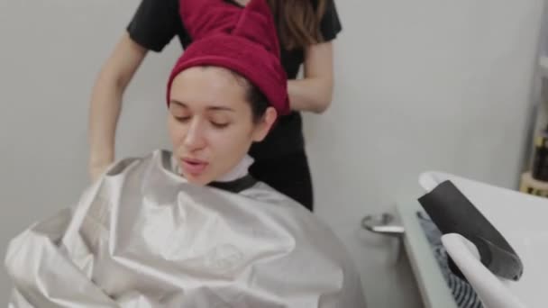 Salon fryzjerski. Fryzjer wyciera swoim klientom włosy w zlewie ręcznikiem po umyciu go. — Wideo stockowe