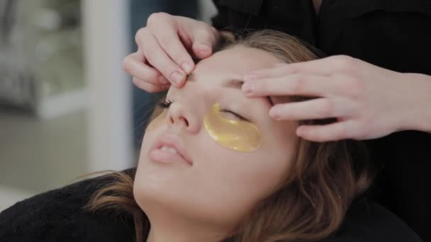 Chica joven en un salón de belleza haciendo masaje facial . — Vídeo de stock