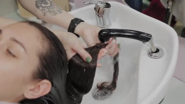 Όμορφη νεαρή κοπέλα πλένουν τα μαλλιά τους στο κομμωτήριο. — Αρχείο Βίντεο