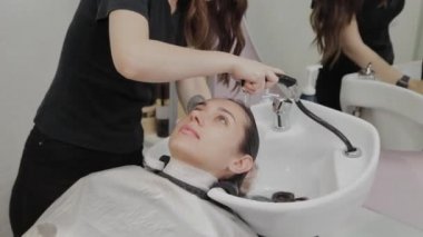 Güzel genç kız kuaförde saçlarını yıkıyor..