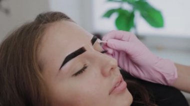 Profesyonel makyöz müşteriye kına ile kaş çizer.