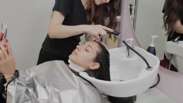 Schöne junge Mädchen waschen ihre Haare beim Friseur. — Stockvideo