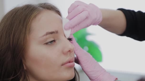 Make-up-Artist schmiert die Augenbrauen der Kundin vor dem Eingriff mit Gel. — Stockvideo