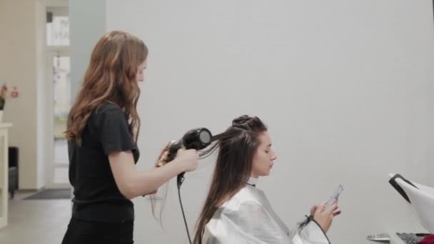 Flicka frisör torkar håret till kund med hårtork på frisör. — Stockvideo