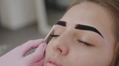 Profesyonel makyöz müşteriye kına ile kaş çizer.