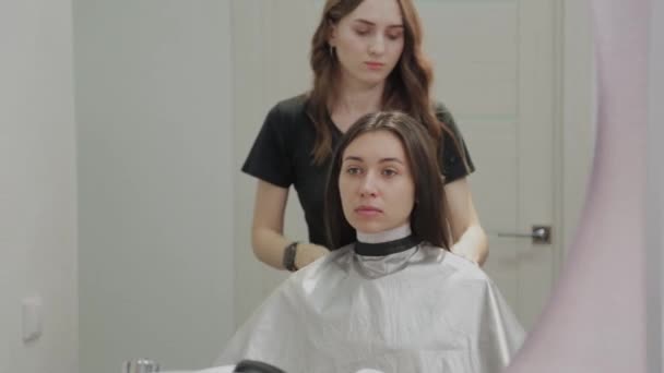 Meisje kapper bereidt een klant voor kapsels. — Stockvideo