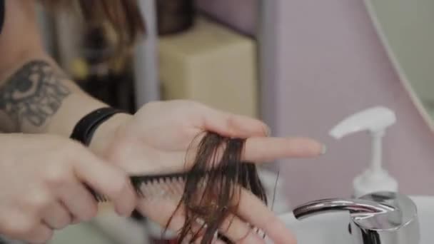 Dívka kadeřník česání mokré vlasy na klienta. — Stock video