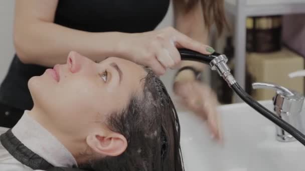Piękna młoda dziewczyna umyć włosy u fryzjera. — Wideo stockowe
