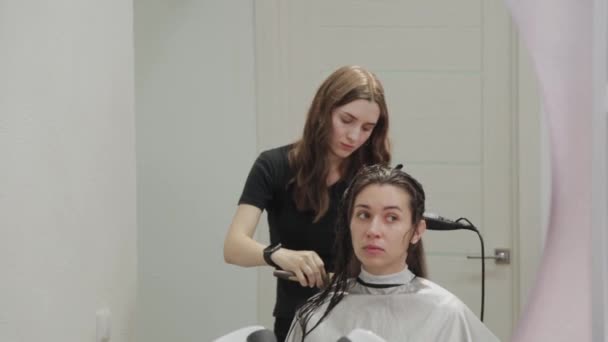 Dívka kadeřník suší vlasy na klienta s fénem na kadeřnictví. — Stock video