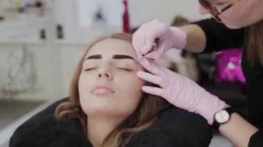 Profesyonel makyöz güzellik salonundaki müşterileri için kaş yoluyor..