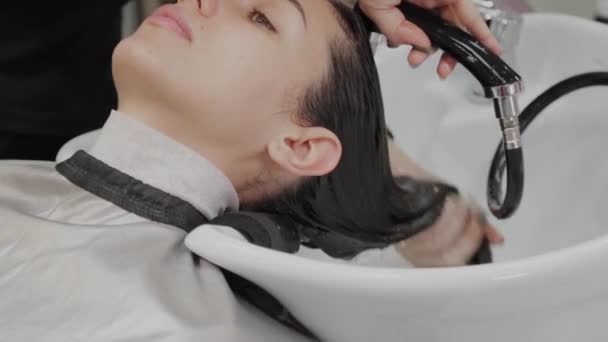 Schöne junge Mädchen waschen ihre Haare beim Friseur. — Stockvideo