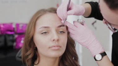 Profesyonel makyöz müşteriye kına ile kaş çizer.