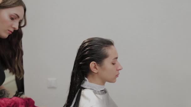 Peluquería. Un peluquero está limpiando el pelo de sus clientes en el lavabo con una toalla después de lavarlo. . — Vídeos de Stock