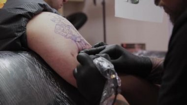 Profesyonel dövme sanatçısı bir adamın kolunda dövme yapar..