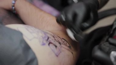Profesyonel dövme sanatçısı bir adamın kolunda dövme yapar..