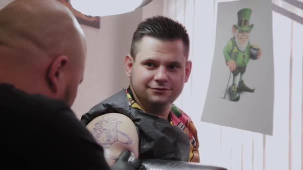 Profissional tatuador faz uma tatuagem no braço de um homem . — Vídeo de Stock