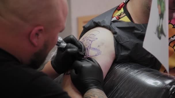 Il tatuatore professionista fa un tatuaggio sul braccio di un uomo . — Video Stock