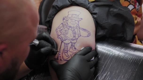 Профессиональный татуировщик делает татуировку на руке мужчины . — стоковое видео