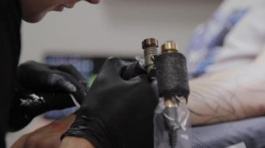 Profesyonel dövme sanatçısı bir adamın kolunda dövme yapar..