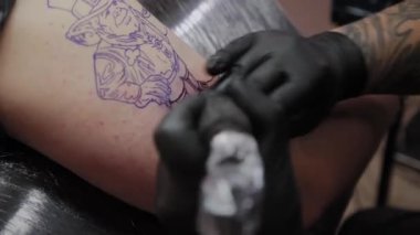 Profesyonel dövme sanatçısı bir adamın kolunda dövme yapar..