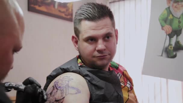 Profi tetováló művész csinál egy tetoválást egy férfi karjára.