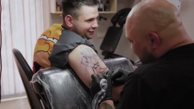 Profesyonel dövme sanatçısı bir adamın kolunda dövme yapar..