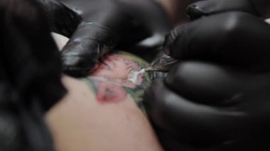 Profesyonel dövme sanatçısı bir adamın kolunda dövme yapar..