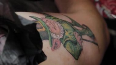 Profesyonel dövme sanatçısı bir adamın kolunda dövme yapar..